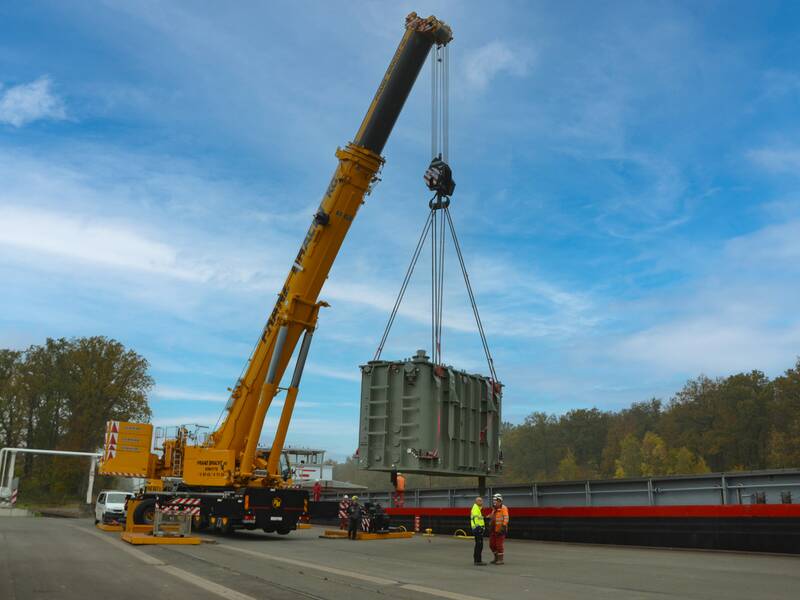 Kranwagen lädt einen Generator auf ein Schiff